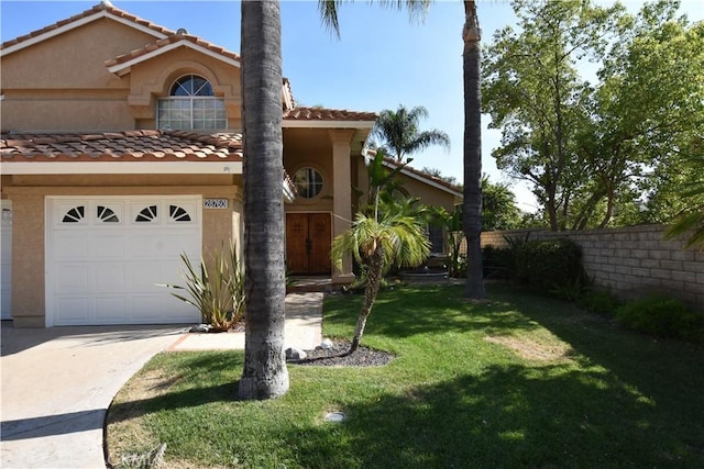 mediterranean / spanish home with fence, a front lawn, concrete driveway, and stucco siding