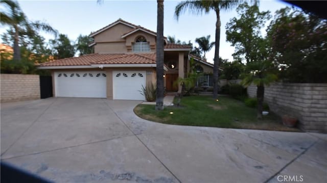 view of front of home with concrete driveway, a tiled roof, an attached garage, fence, and stucco siding