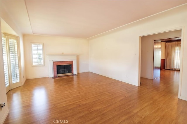 unfurnished living room featuring light wood finished floors and a brick fireplace