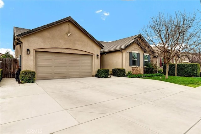 ranch-style house with concrete driveway, a tile roof, an attached garage, fence, and stucco siding