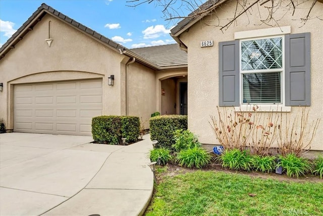 view of front of house with a garage, concrete driveway, a tiled roof, and stucco siding