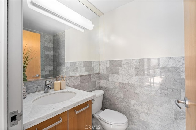 half bath featuring tile walls, vanity, and toilet