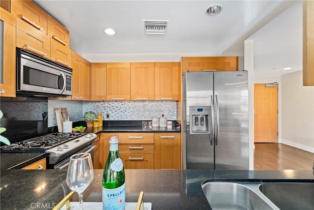 kitchen with visible vents, decorative backsplash, appliances with stainless steel finishes, a sink, and wood finished floors