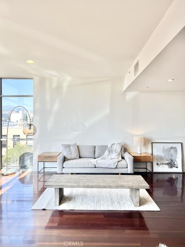 living area with floor to ceiling windows, visible vents, and wood finished floors