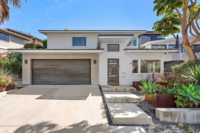 contemporary house with concrete driveway, an attached garage, and stucco siding