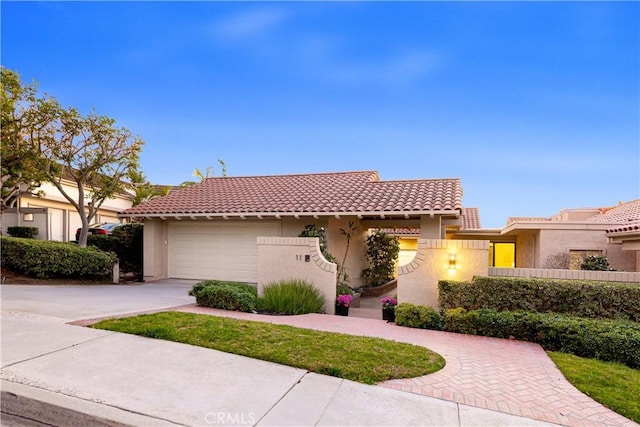 view of front of house with driveway, a tiled roof, an attached garage, and stucco siding