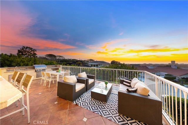 patio terrace at dusk with area for grilling, exterior kitchen, outdoor lounge area, a sink, and outdoor dining space