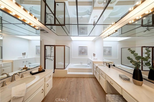 full bath featuring a skylight, wood finished floors, a garden tub, vanity, and a shower stall