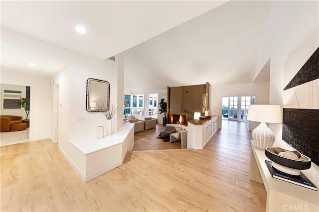 hallway featuring lofted ceiling, recessed lighting, light wood-type flooring, and baseboards