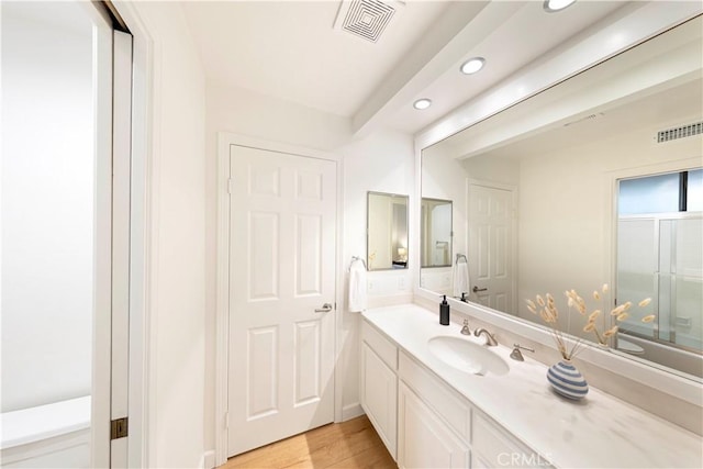 full bath featuring recessed lighting, visible vents, vanity, and wood finished floors