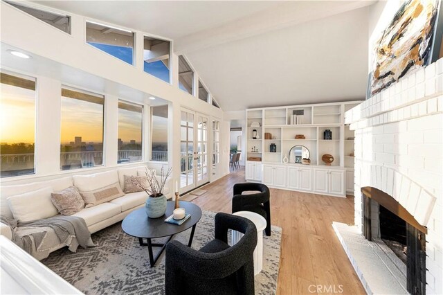 11 Montpellier, Newport Beach, CA 92660 - living area featuring french doors, beam ceiling, high vaulted ceiling, light wood-style flooring, and a brick fireplace