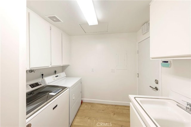 laundry area with light wood-style floors, washing machine and dryer, cabinet space, and visible vents