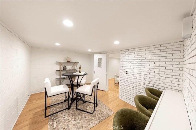 dining space with brick wall, light wood-style flooring, and recessed lighting