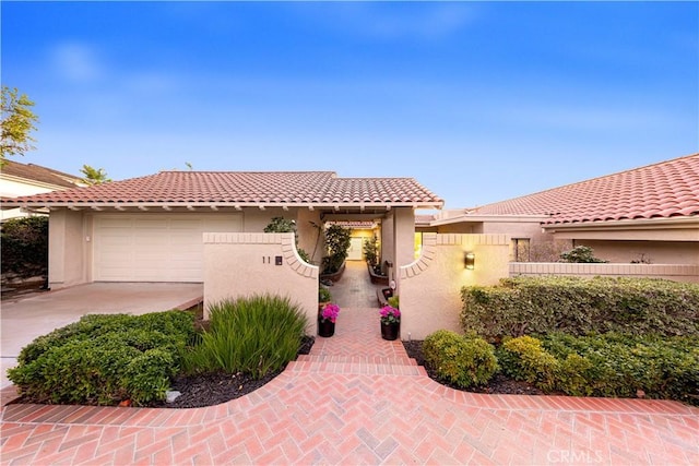 mediterranean / spanish home with driveway, a garage, a tiled roof, fence, and stucco siding