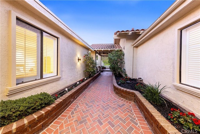 view of side of home featuring a patio area, a tiled roof, and stucco siding