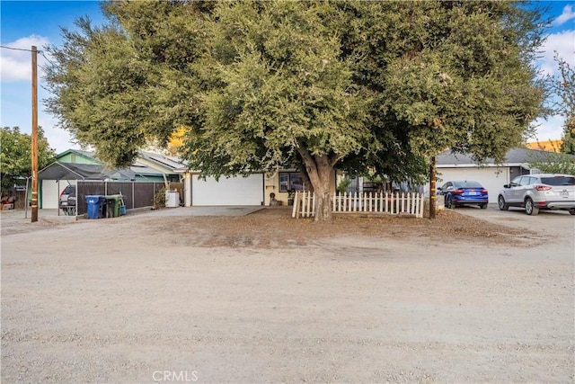 obstructed view of property featuring a garage, driveway, and fence