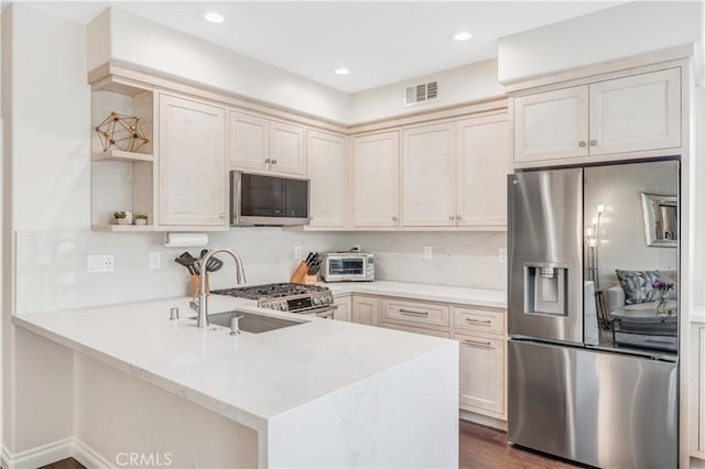 kitchen featuring appliances with stainless steel finishes, light countertops, visible vents, and a peninsula