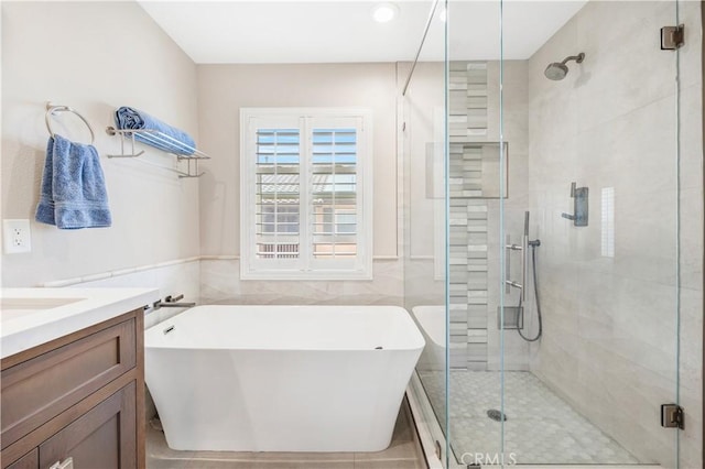 full bathroom with a soaking tub, a shower stall, vanity, and tile walls