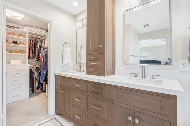 full bath with a walk in closet, visible vents, a sink, and double vanity