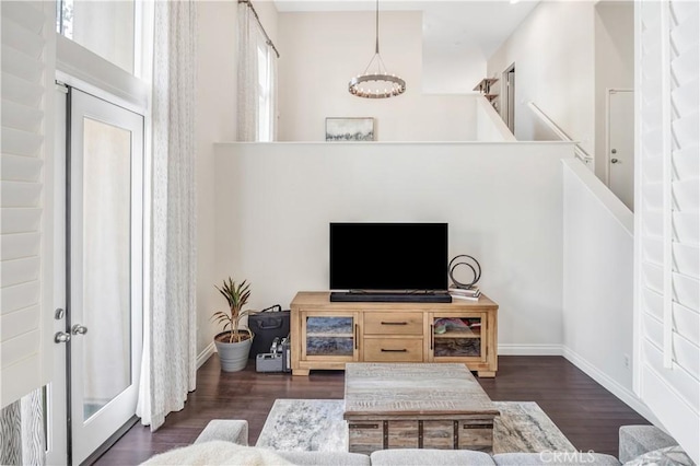 living room with dark wood-style floors, baseboards, and a notable chandelier