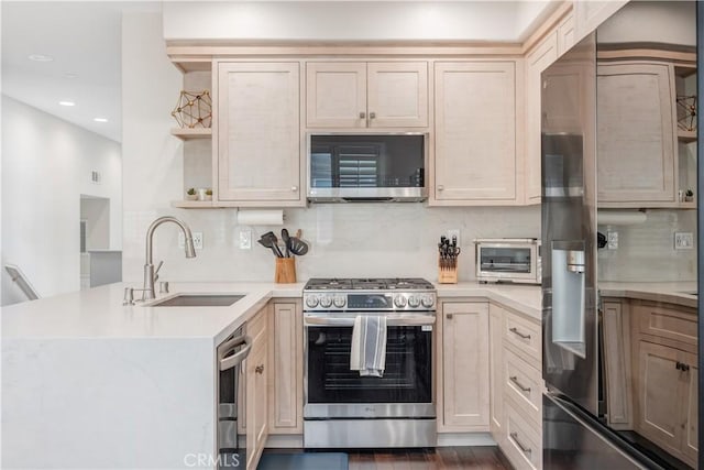 kitchen with decorative backsplash, appliances with stainless steel finishes, a peninsula, light countertops, and a sink