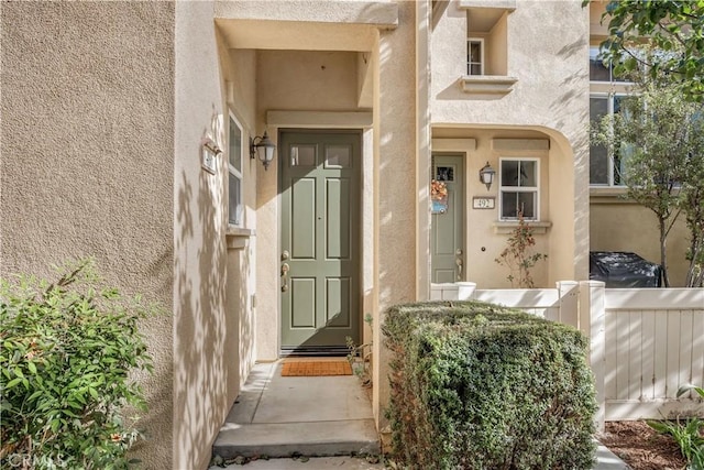 entrance to property with fence and stucco siding