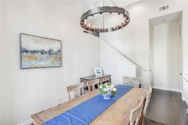 dining room featuring wood-type flooring, visible vents, a notable chandelier, and baseboards