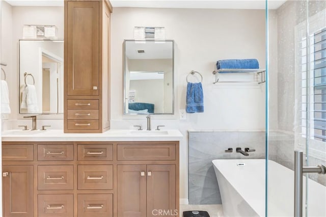 bathroom featuring double vanity, a freestanding tub, tile walls, and a sink