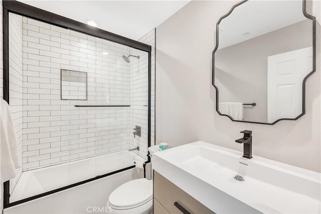 bathroom featuring toilet, combined bath / shower with glass door, and vanity