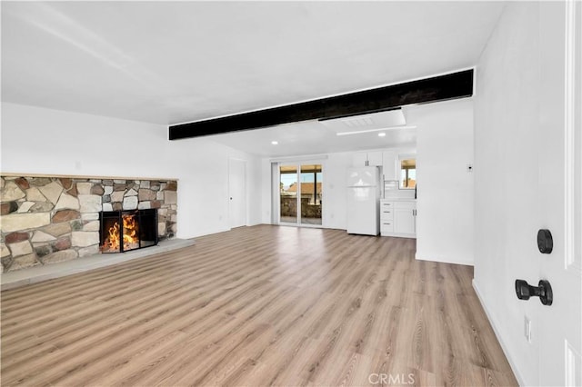 unfurnished living room featuring light wood finished floors, a fireplace, and beam ceiling