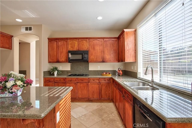 23531 Hobart Ct, Murrieta, CA 92562 - kitchen featuring black appliances, light stone countertops, light tile patterned floors, arched walkways, and brown cabinets