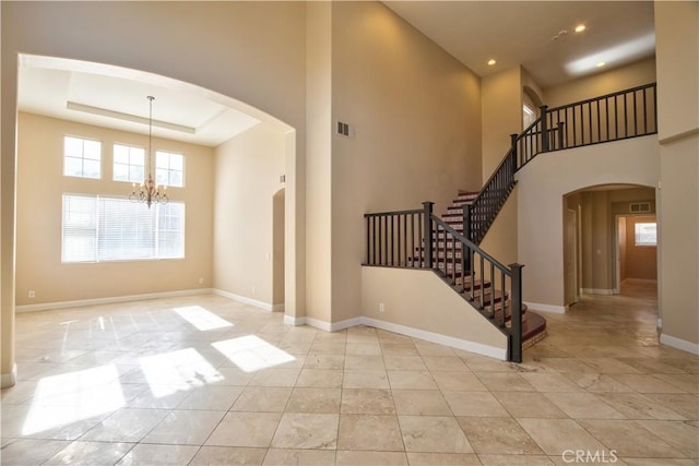 foyer entrance featuring arched walkways, visible vents, a notable chandelier, and baseboards