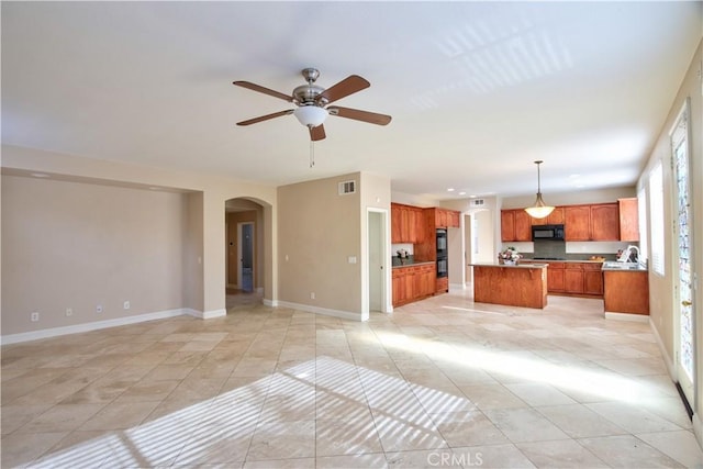 unfurnished living room featuring visible vents, arched walkways, light tile patterned floors, baseboards, and ceiling fan