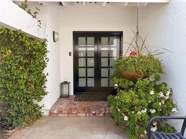 view of exterior entry with french doors and stucco siding