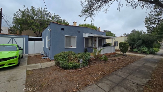 view of front facade featuring covered porch, fence, and stucco siding