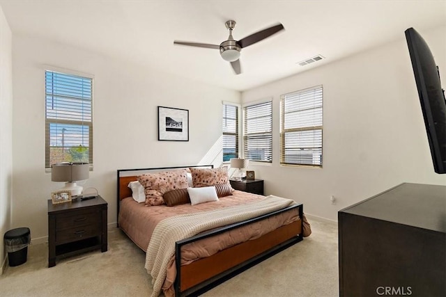 bedroom with a ceiling fan, light colored carpet, visible vents, and baseboards