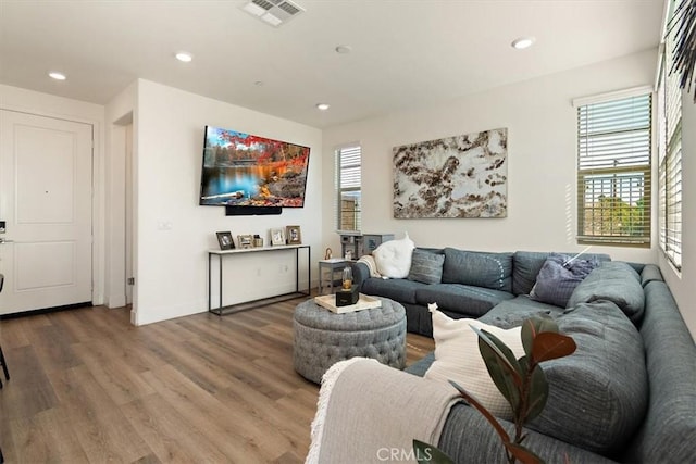 living room with a wealth of natural light, visible vents, recessed lighting, and wood finished floors