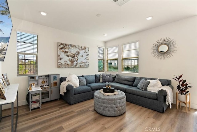 living area with baseboards, visible vents, wood finished floors, and recessed lighting