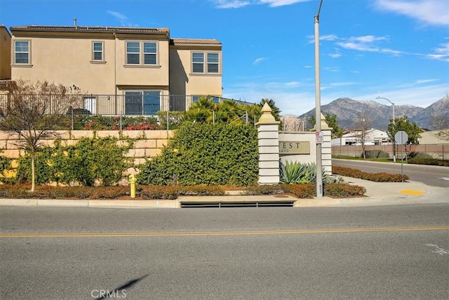 view of front facade with a tiled roof, fence, a mountain view, and stucco siding