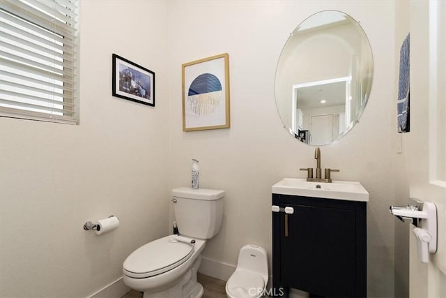 bathroom featuring toilet, baseboards, and vanity