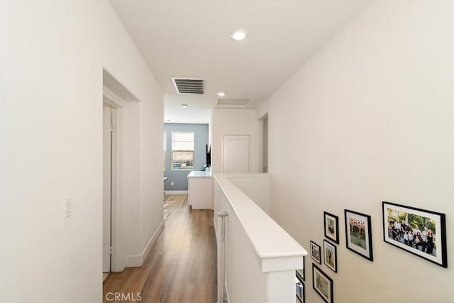 hall featuring attic access, visible vents, baseboards, an upstairs landing, and light wood-type flooring