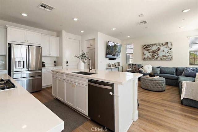 kitchen with open floor plan, black appliances, a sink, and light countertops