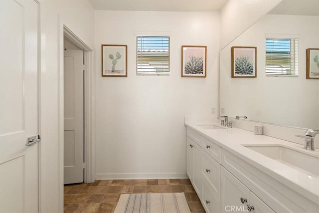 full bathroom with double vanity, baseboards, and a sink