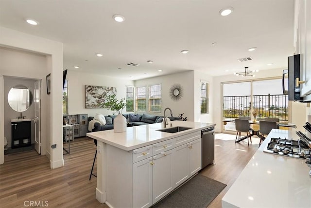 kitchen with an island with sink, appliances with stainless steel finishes, white cabinets, and light countertops