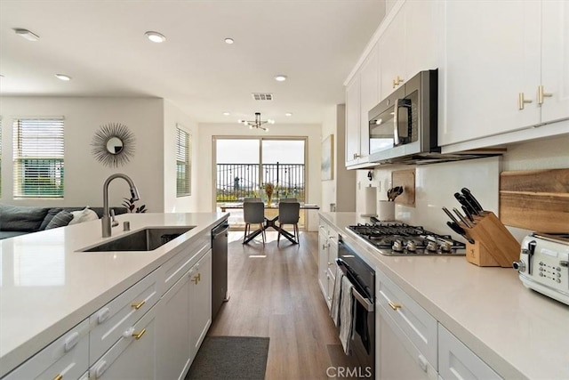 kitchen with stainless steel appliances, a sink, light countertops, and white cabinets