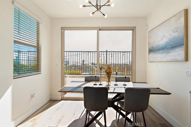 dining space featuring a chandelier, wood finished floors, and baseboards