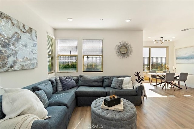 living area with a wealth of natural light, visible vents, baseboards, and wood finished floors