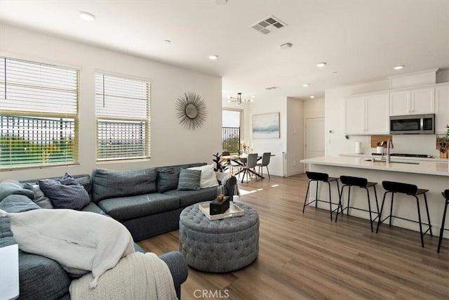 living room featuring recessed lighting, dark wood-style flooring, and visible vents