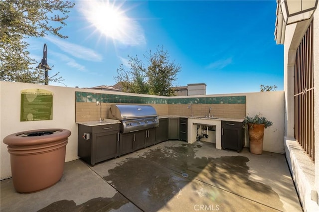 view of patio featuring exterior kitchen, area for grilling, a sink, and fence