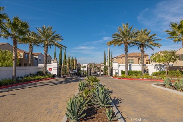 view of street featuring street lights, a gated entry, curbs, a gate, and a residential view